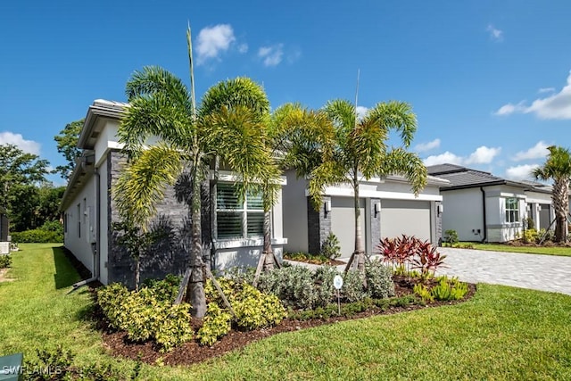 view of front of house featuring a garage, a front lawn, decorative driveway, and stucco siding