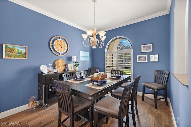 dining space with ornamental molding, a notable chandelier, baseboards, and wood finished floors