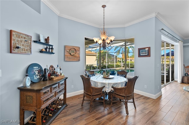 dining area with ornamental molding, a notable chandelier, baseboards, and wood finished floors