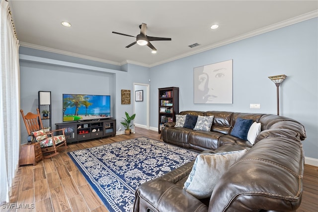 living room featuring ceiling fan, wood finished floors, visible vents, baseboards, and ornamental molding