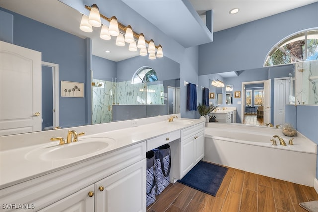 bathroom featuring double vanity, wood finish floors, a sink, and a marble finish shower