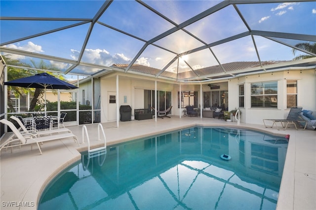 pool with a patio area, ceiling fan, and glass enclosure