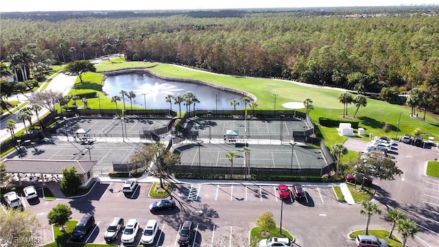 aerial view with view of golf course, a water view, and a view of trees