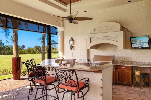 view of patio featuring grilling area, ceiling fan, an outdoor bar, and exterior kitchen