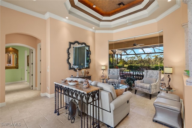 living room featuring a tray ceiling, ceiling fan, and crown molding