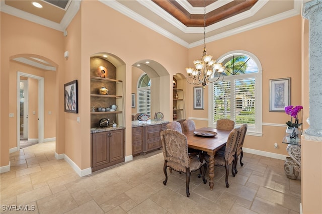 dining area featuring built in features, a towering ceiling, a chandelier, and ornamental molding