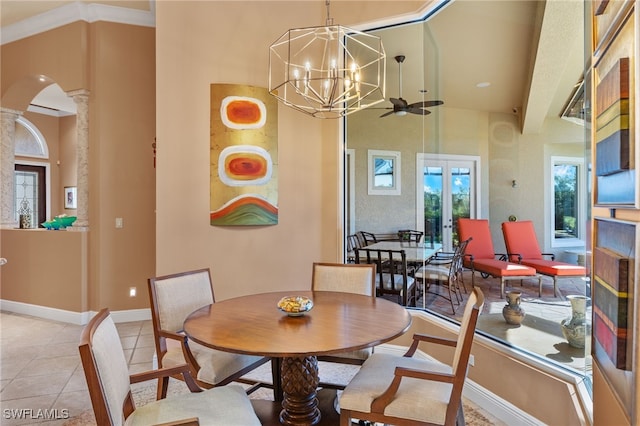 tiled dining room with ceiling fan with notable chandelier, ornate columns, and crown molding