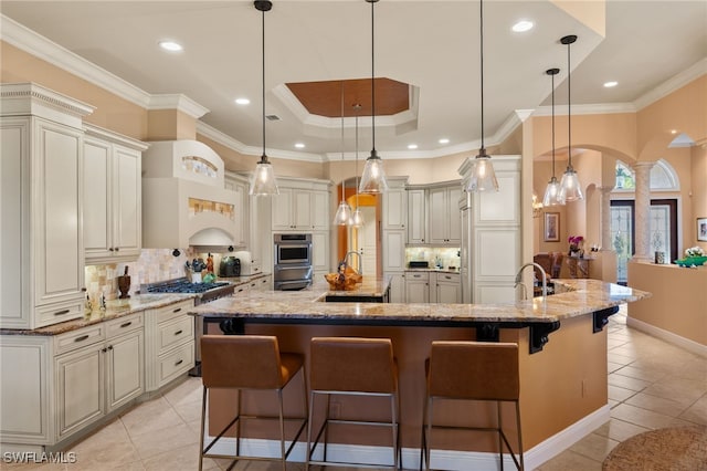 kitchen with decorative light fixtures, light stone counters, a large island, and a breakfast bar area