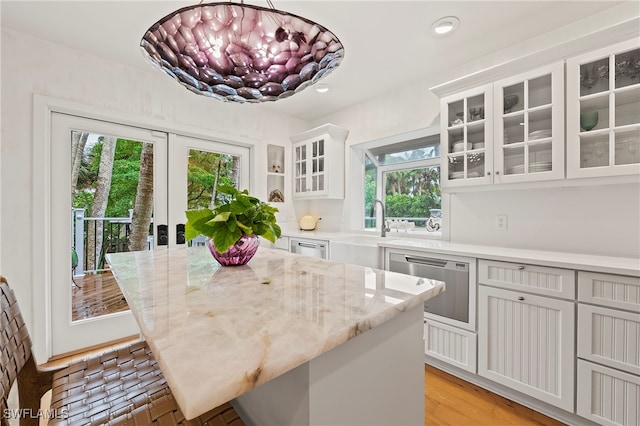 kitchen with pendant lighting, light stone counters, and a healthy amount of sunlight