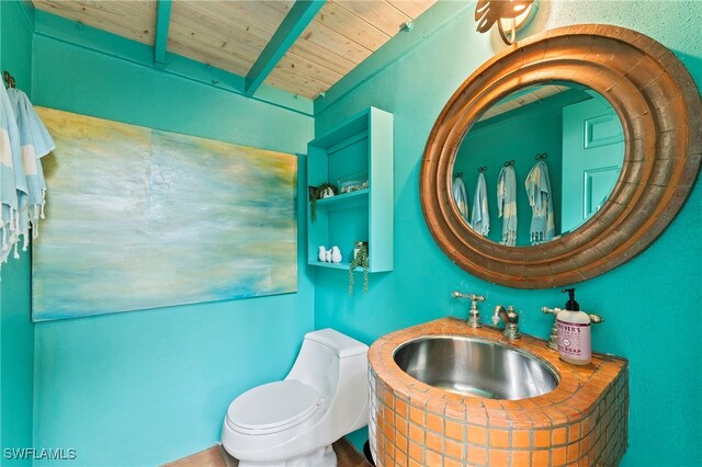 bathroom featuring beam ceiling, sink, wood ceiling, and toilet