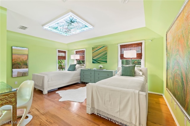 bedroom with vaulted ceiling, light hardwood / wood-style flooring, and multiple windows