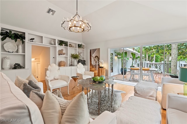 living room with hardwood / wood-style floors, lofted ceiling, and a notable chandelier