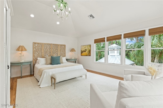 bedroom with a notable chandelier, light wood-type flooring, and lofted ceiling