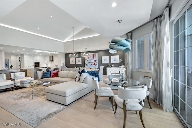 living room with a chandelier, light hardwood / wood-style floors, and vaulted ceiling