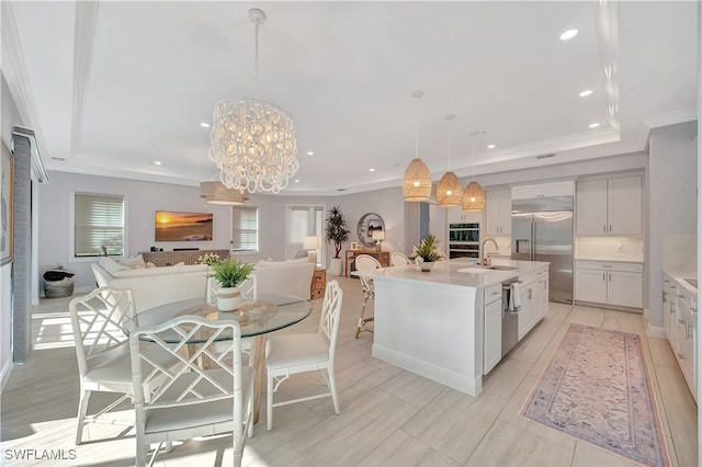 kitchen with sink, a notable chandelier, decorative light fixtures, a center island with sink, and appliances with stainless steel finishes