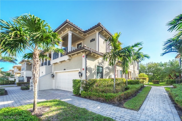 mediterranean / spanish-style home featuring a garage and a balcony