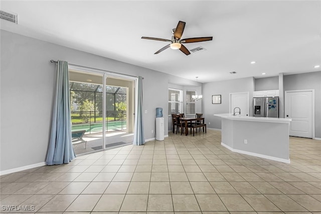 interior space featuring light tile patterned floors and ceiling fan with notable chandelier