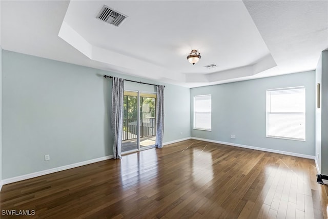 unfurnished room with dark hardwood / wood-style floors and a raised ceiling