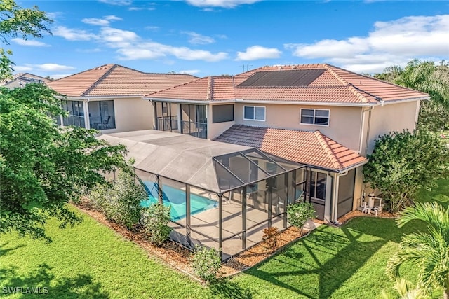 rear view of property with glass enclosure, a patio area, and a lawn