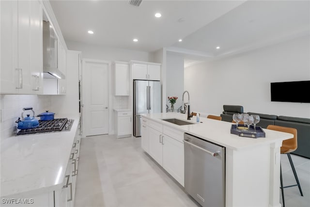 kitchen featuring backsplash, white cabinetry, an island with sink, and appliances with stainless steel finishes