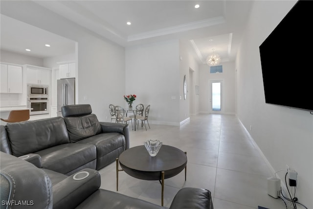 tiled living room with a raised ceiling, crown molding, and a notable chandelier