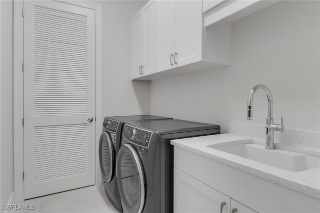 clothes washing area featuring washer and clothes dryer, sink, and cabinets