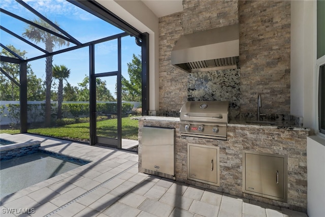 view of patio / terrace featuring glass enclosure, sink, a jacuzzi, area for grilling, and exterior kitchen