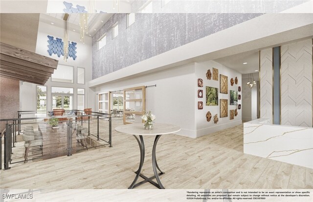 interior space with light wood-type flooring, a towering ceiling, and an inviting chandelier