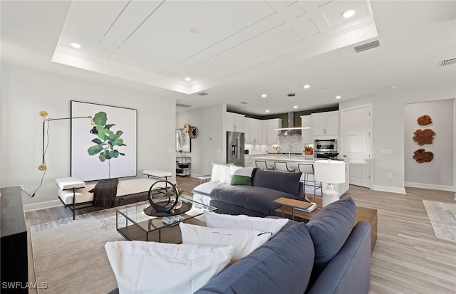 living room featuring a tray ceiling and light hardwood / wood-style flooring