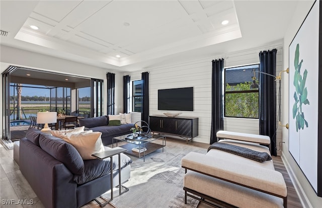 living room featuring a tray ceiling, a wealth of natural light, and light hardwood / wood-style floors