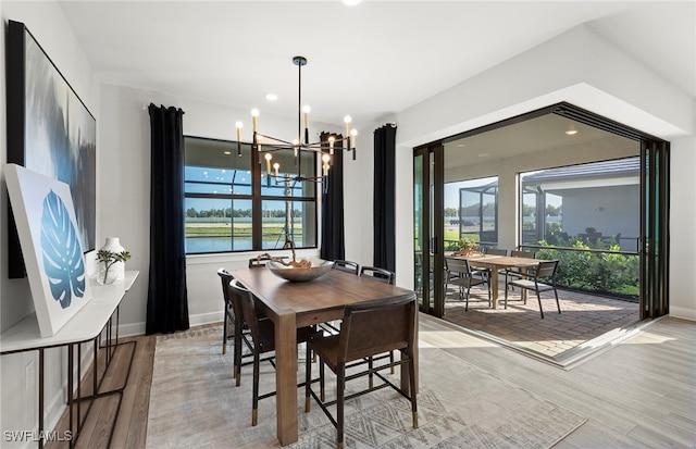 dining area with plenty of natural light, a water view, light wood-type flooring, and a chandelier