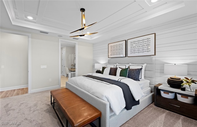 bedroom featuring a tray ceiling, light carpet, and ornamental molding