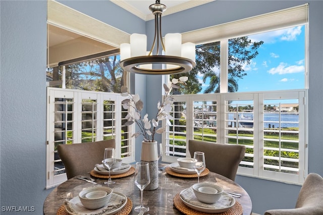 dining room with an inviting chandelier, a water view, and ornamental molding