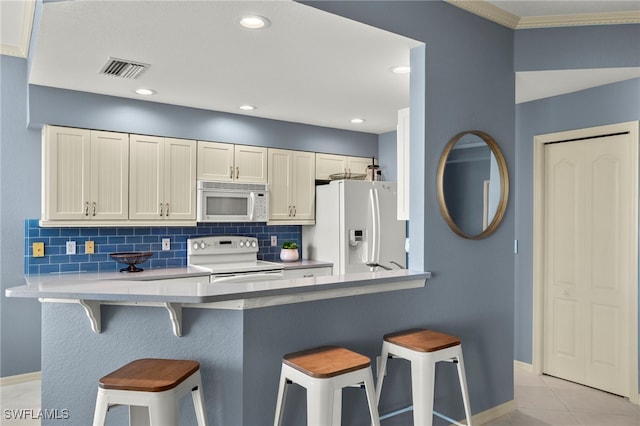 kitchen with kitchen peninsula, tasteful backsplash, white appliances, light tile patterned floors, and a breakfast bar area