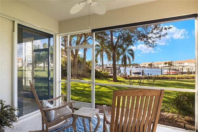 sunroom featuring plenty of natural light, ceiling fan, and a water view