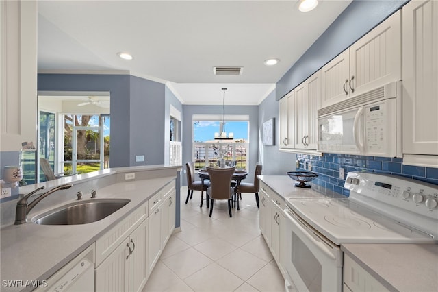 kitchen with sink, white cabinets, hanging light fixtures, and white appliances