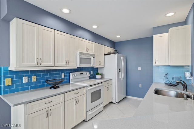 kitchen with backsplash, white appliances, sink, light tile patterned floors, and white cabinets