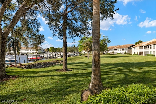 view of property's community with a boat dock, a yard, and a water view