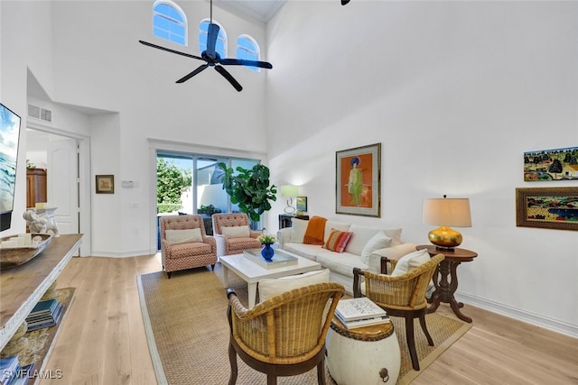 living room featuring a high ceiling, light hardwood / wood-style flooring, and ceiling fan