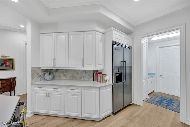 kitchen with crown molding, built in refrigerator, decorative backsplash, light hardwood / wood-style floors, and white cabinetry