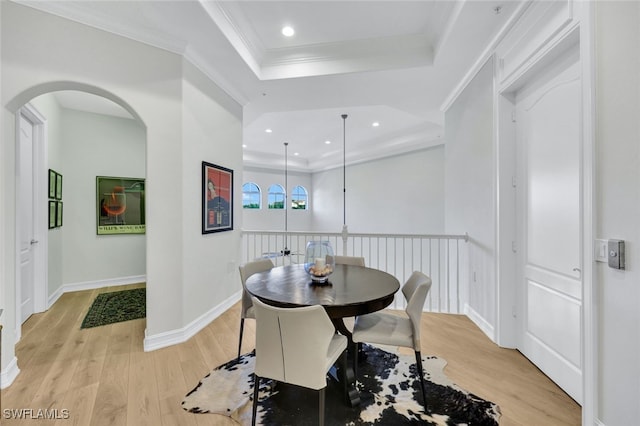 dining space with light hardwood / wood-style floors, crown molding, and a tray ceiling