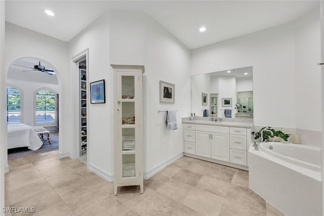 bathroom with vanity, ceiling fan, and tiled tub