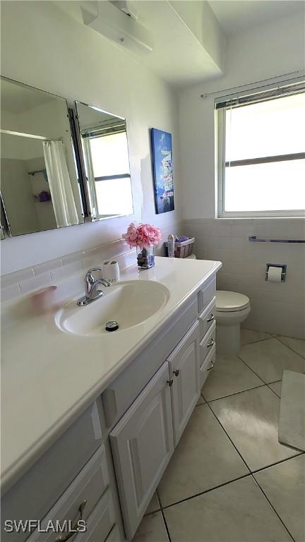 bathroom featuring toilet, tile patterned floors, curtained shower, vanity, and tile walls