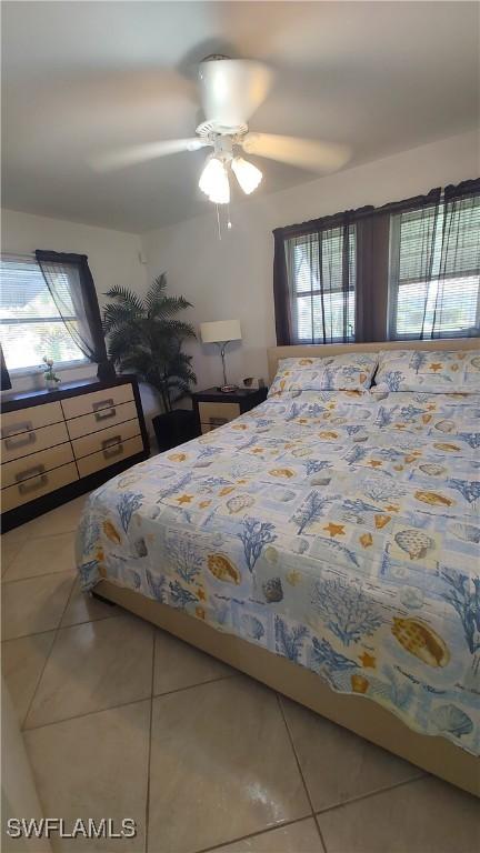 bedroom with multiple windows, ceiling fan, and tile patterned flooring