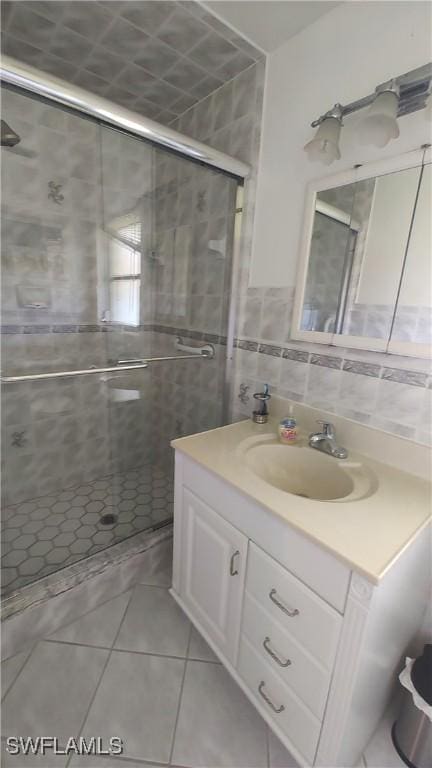 bathroom featuring a stall shower, tile patterned flooring, tile walls, and vanity