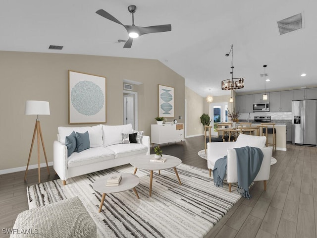 living room featuring ceiling fan with notable chandelier, light hardwood / wood-style floors, and lofted ceiling