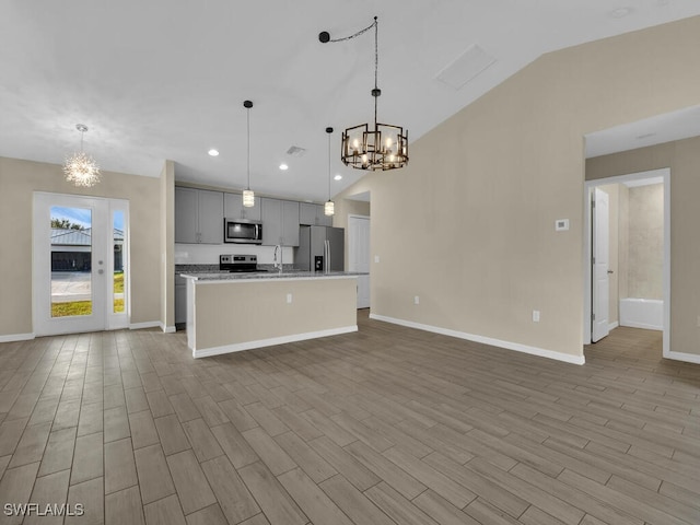 kitchen featuring stainless steel appliances, a notable chandelier, light hardwood / wood-style floors, gray cabinets, and a center island with sink