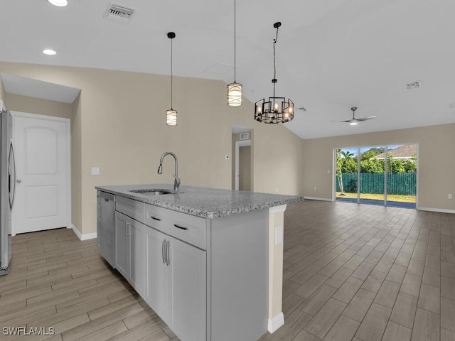 kitchen featuring light stone countertops, ceiling fan, sink, pendant lighting, and lofted ceiling