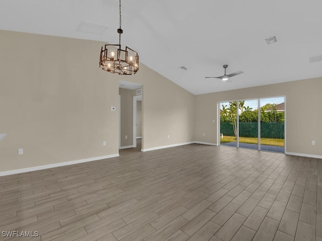 spare room with ceiling fan with notable chandelier, light hardwood / wood-style floors, and vaulted ceiling