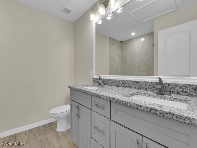 bathroom with hardwood / wood-style flooring, vanity, toilet, and tiled shower